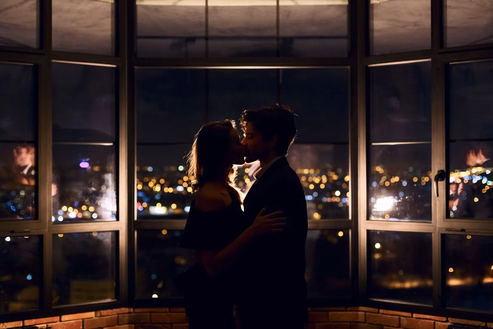 couple kissing by a wide window